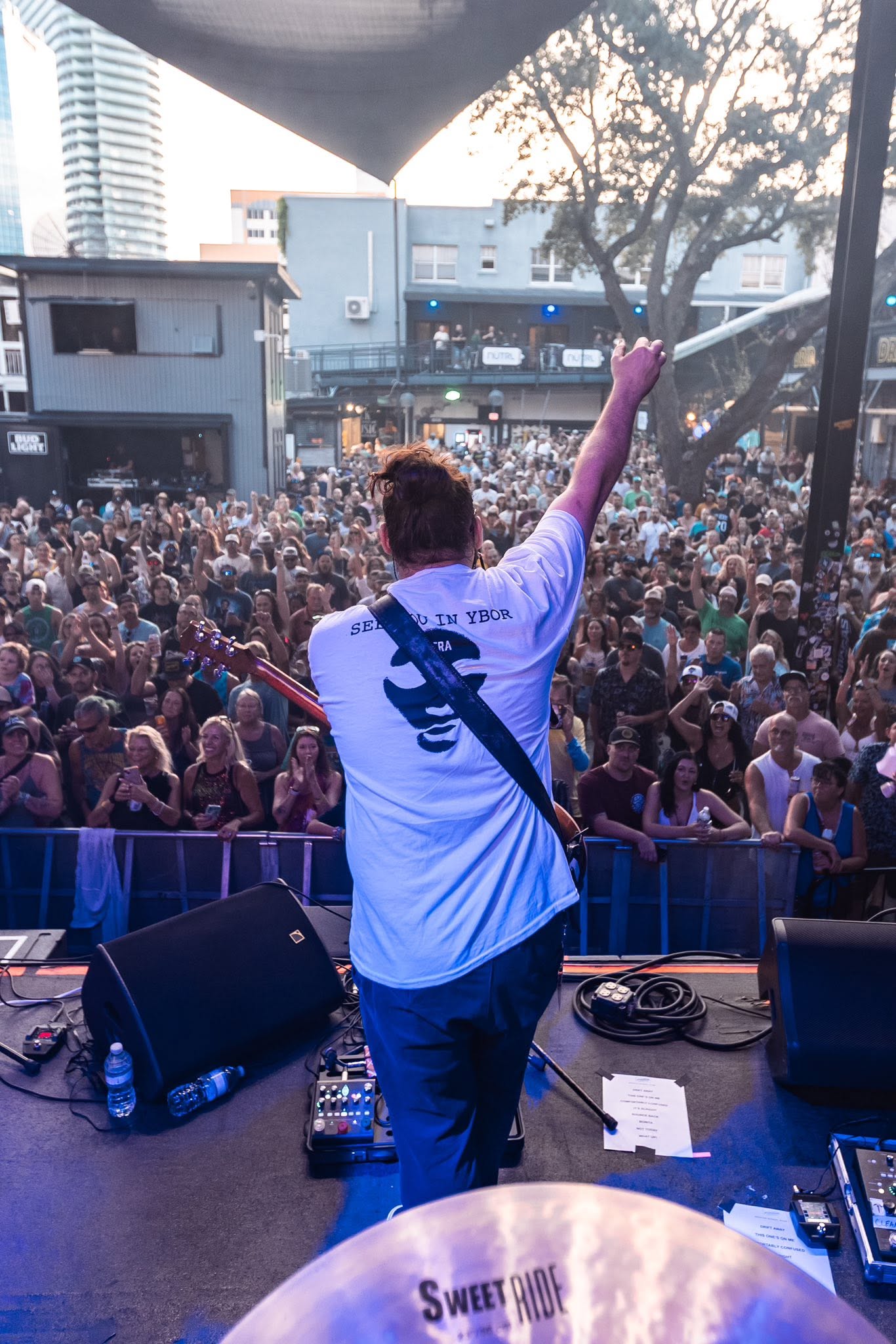 Seranation guitarist raising a fist to a packed outdoor crowd